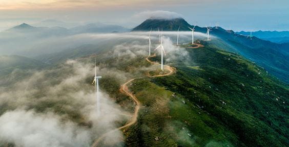 Windpark auf grünem Hügel im Nebel – Grüne Anleihen: ein Beitrag zum Übergang in eine nachhaltigere Zukunft